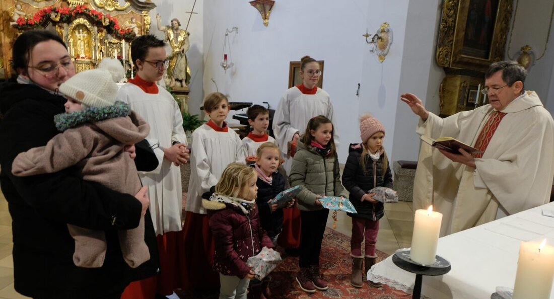 Floß. Pfarrer Max Früchtl und die katholische Pfarrgemeinde St. Johannes der Täufer segneten am Fest der Heiligen Familie Kinder nach dem Gottesdienst. Kinder brachten Geschenkpakete mit, die sie am Altar tauschten und erhielten zur Erinnerung ein Bildchen.