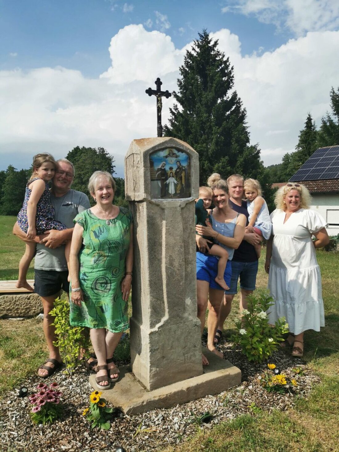 Krücklasmühle. Die Künstlerin Maria Hertrich hat das stark verwitterte Feldkreuz mit dem Bildnis der Heiligen Familie behutsam restauriert, nun leuchten die Farben wieder. Familie Schleicher stellte es mit drei Generationen vor.