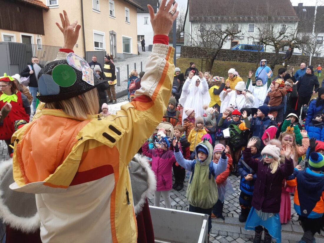 Parkstein. Mit „Kinderhaus Helau“ zogen die Kinder des Kinderhauses St. Pankratius zum Start der Faschingsferien mit Eltern und Personal zum Rathaus. Zwei Bulldogs und ein Auto begleiteten den Zug; Julia, Noah und Ida winkten.